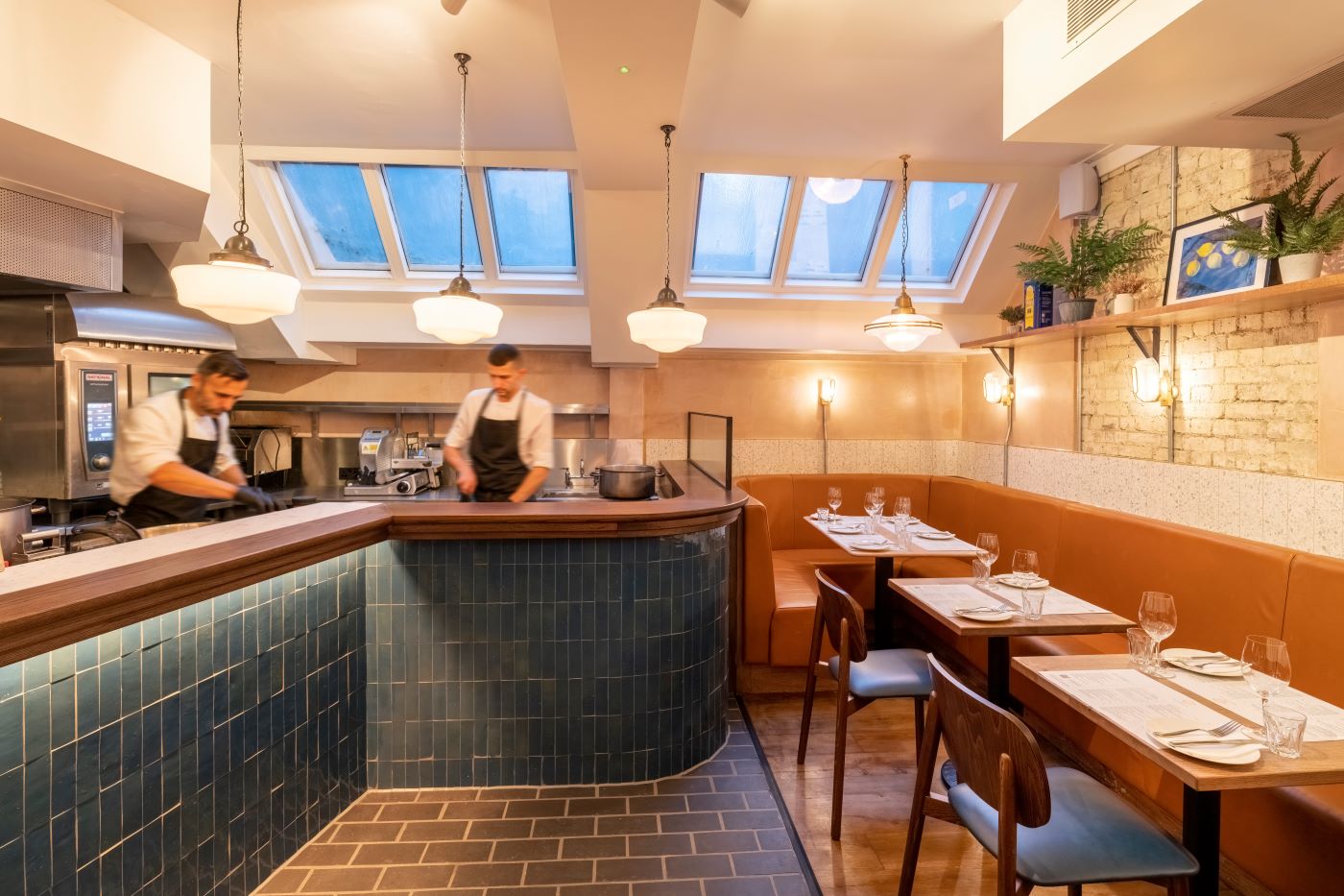Two kitchen staff preparing dishes under a warm light