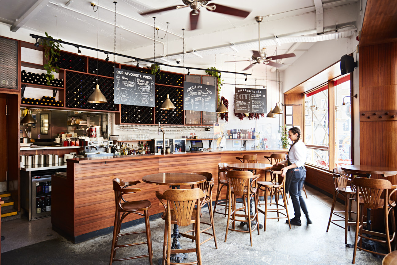 A waitress sorting tables and chairs in front of the bar
