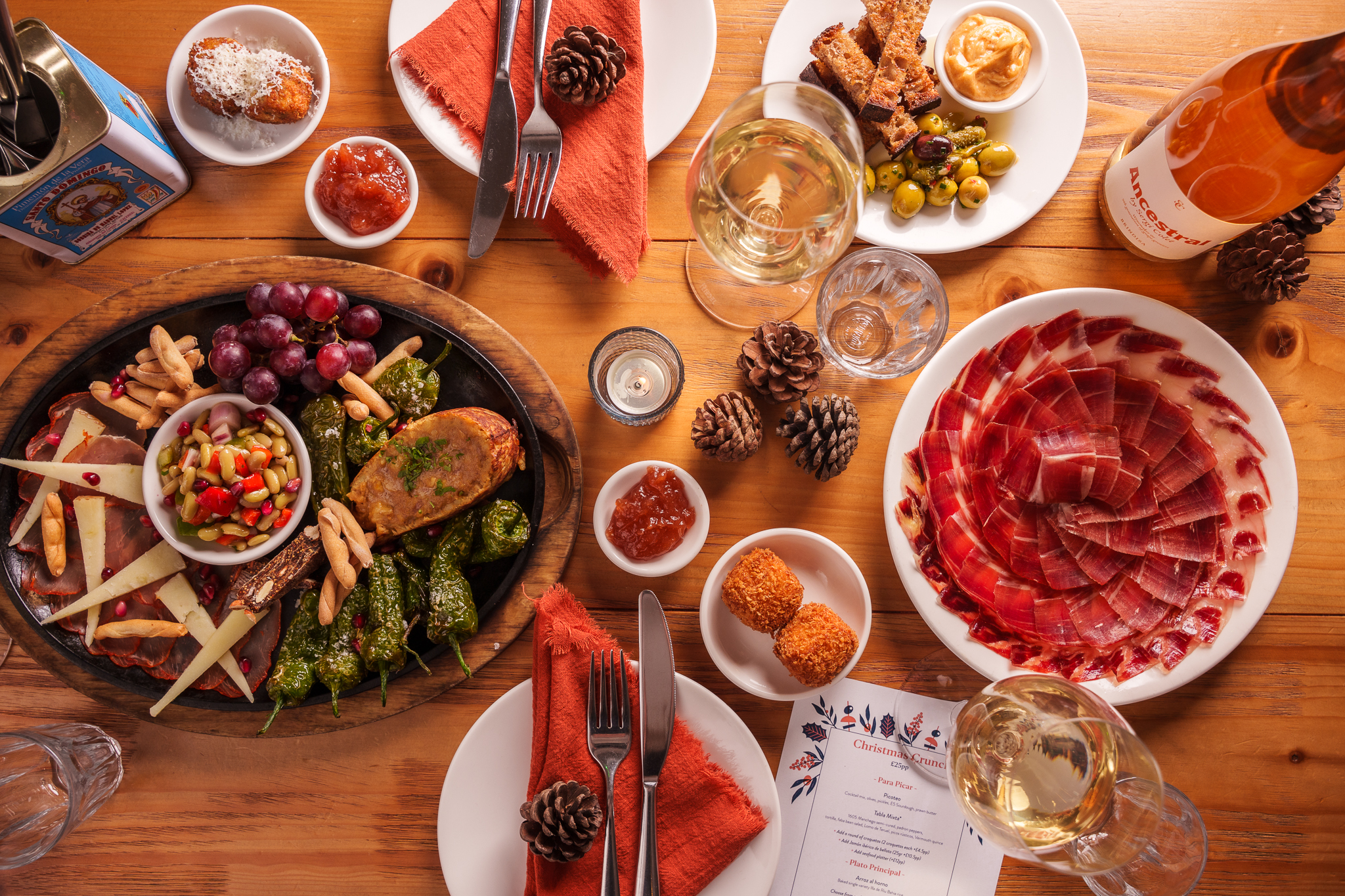 An aerial view of a table featuring a variety of tapas dishes, including croquettes, olives, and jamón iberico