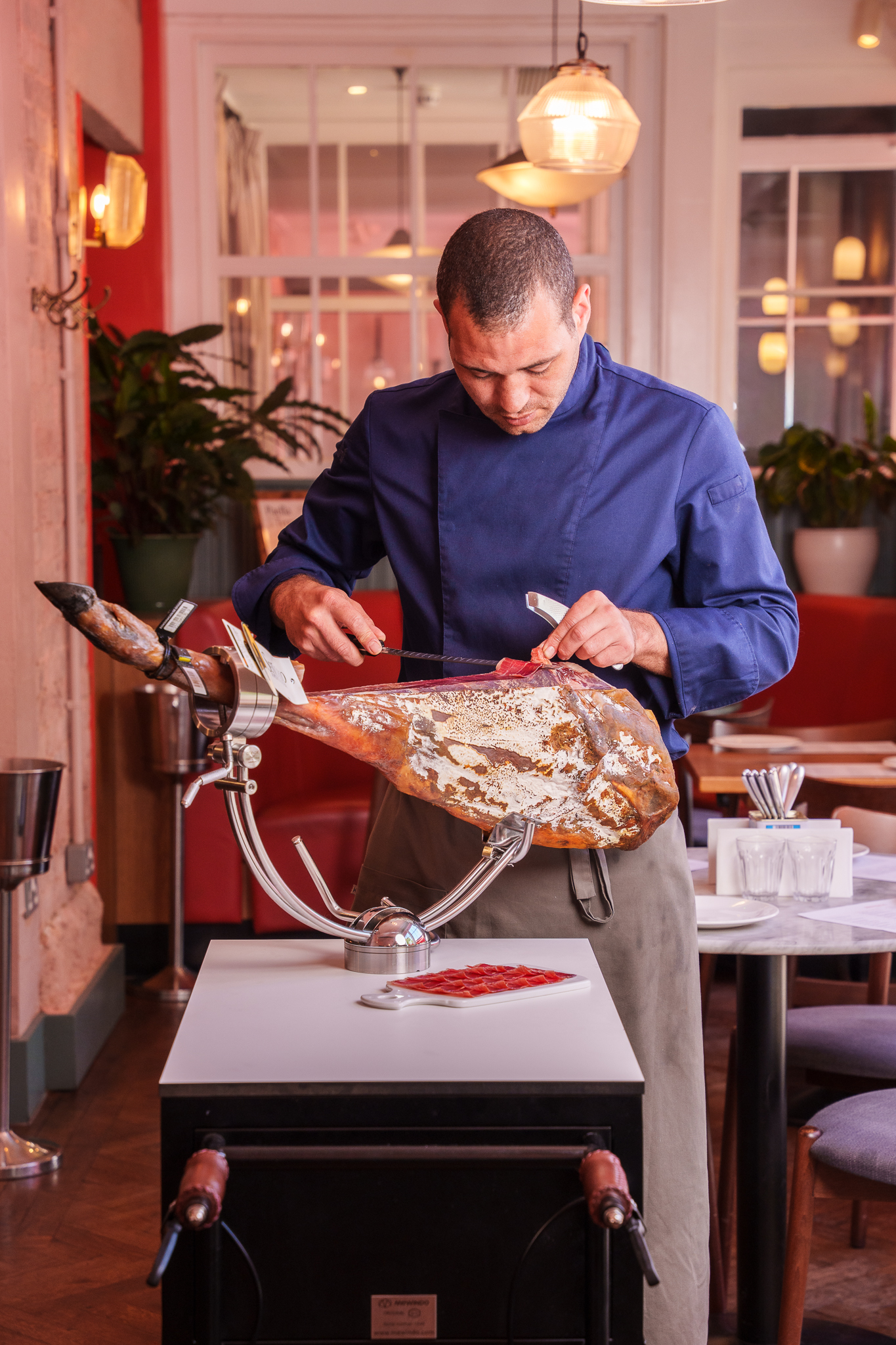 Brindisa Tapas' master jamón carver Zac, carving a jamón leg in a Brindisa Tapas restaurant.
